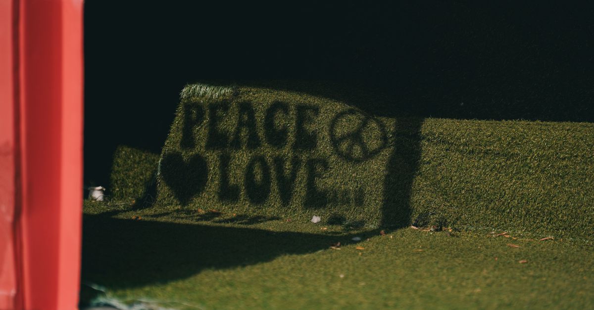 Creative shadow of 'Peace Love' sign with peace symbol on artificial grassmat