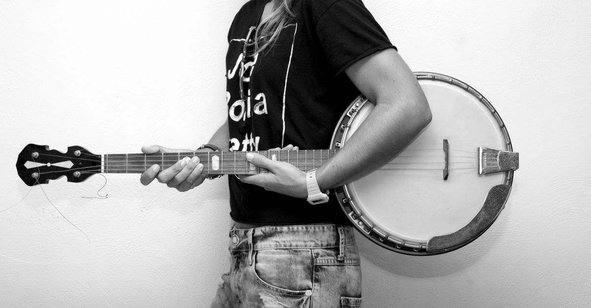 A young musician holding a banjo, captured in a studio setting. Black and white photography.