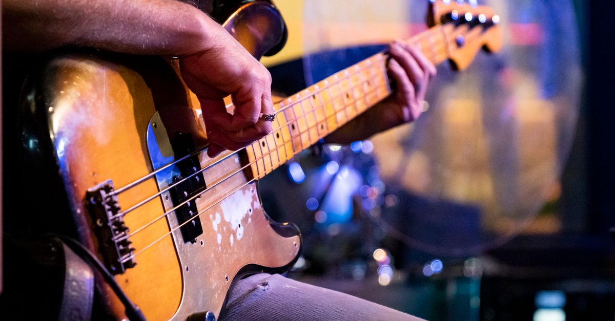 Detailed close-up of a musician playing a vintage bass guitar during a live performance.