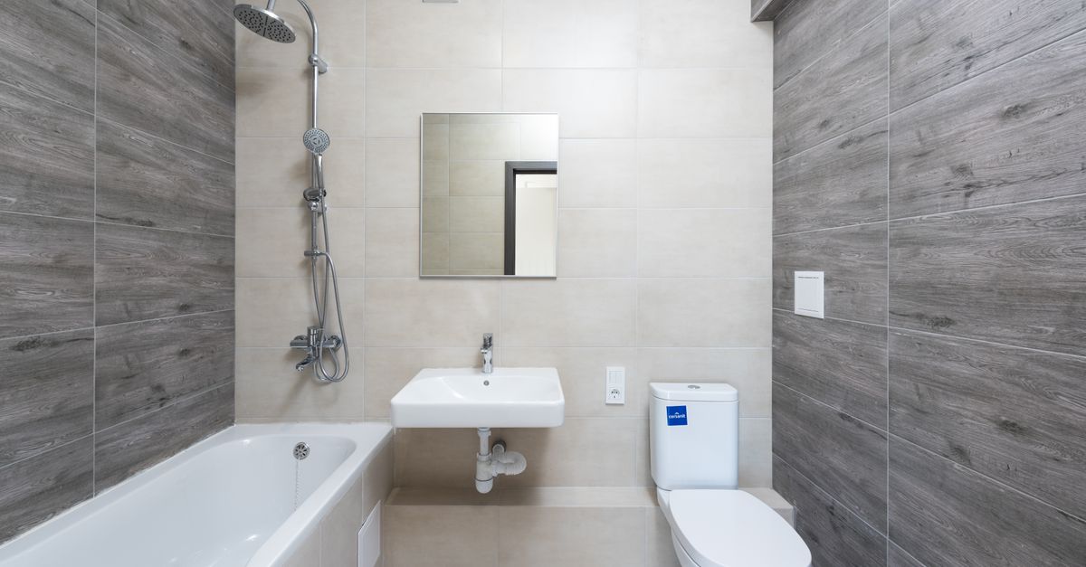 A contemporary bathroom features a bathtub, sink, and toilet with wood accents.