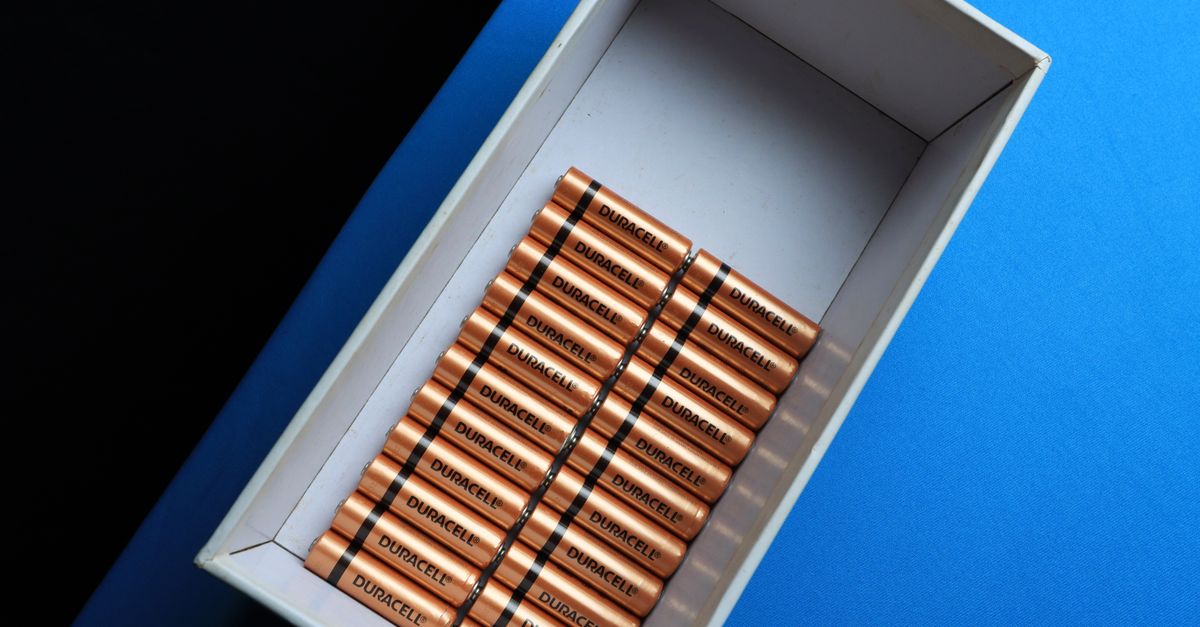 Top view of neatly arranged batteries in a box on a contrasting blue surface.
