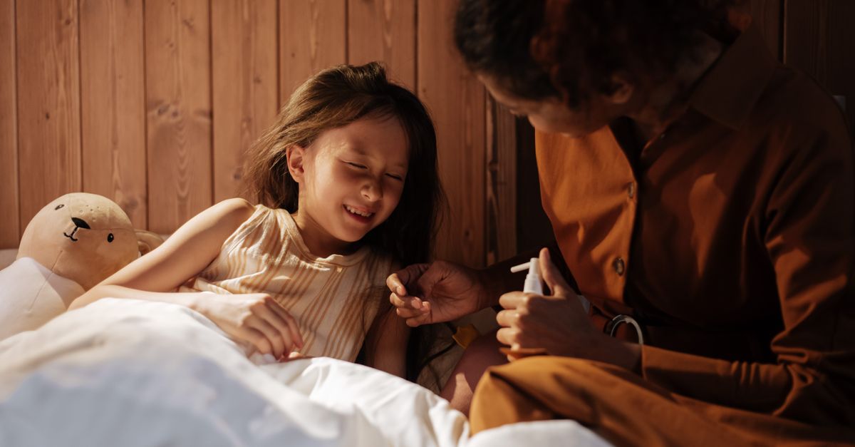 A caring mother comforts her sick daughter in a cozy bedroom setting.