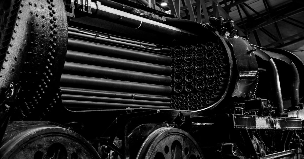 Black and white image of a vintage steam train engine showcasing intricate metallic details.