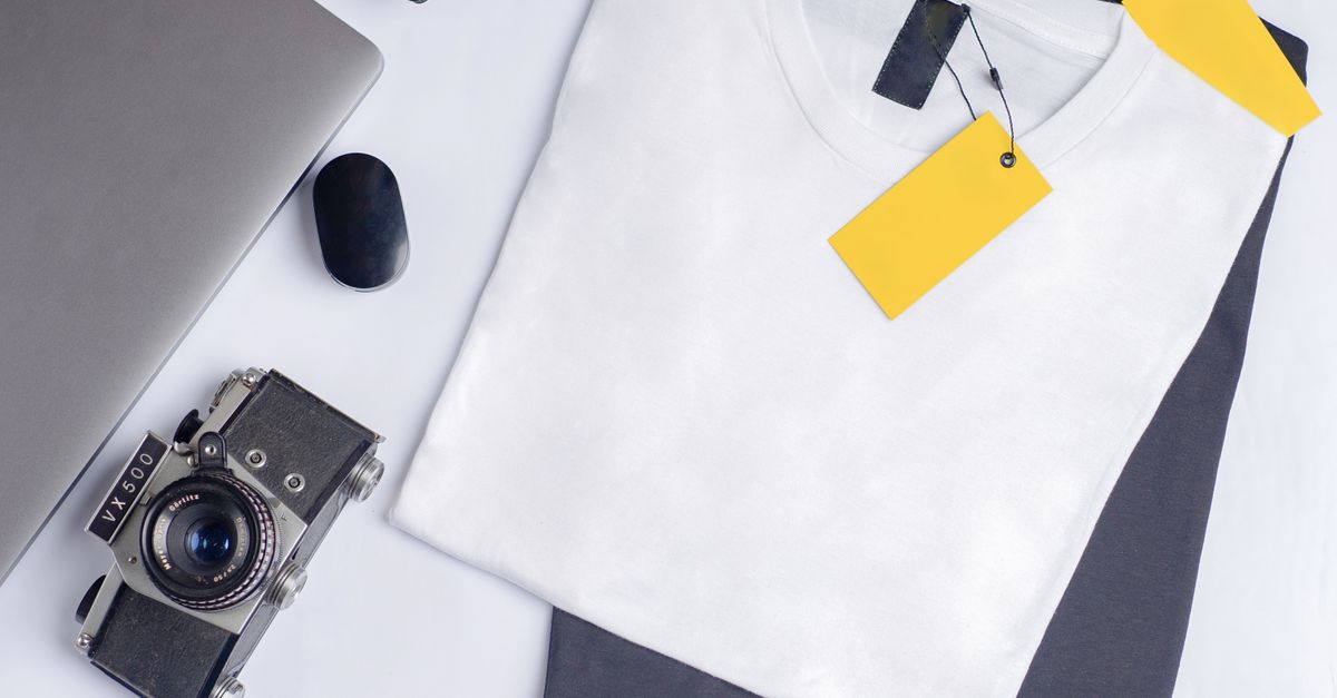 Stylish flat lay featuring a vintage camera, clothing, and laptop on a clean white background.