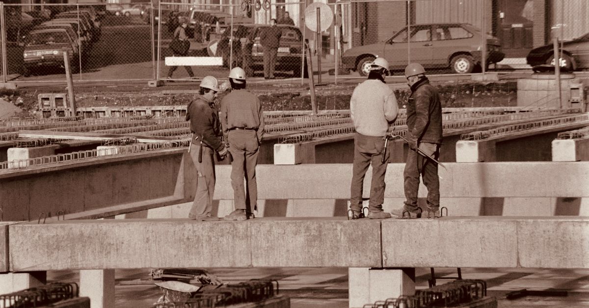Group of construction workers discussing plans on an urban construction site.