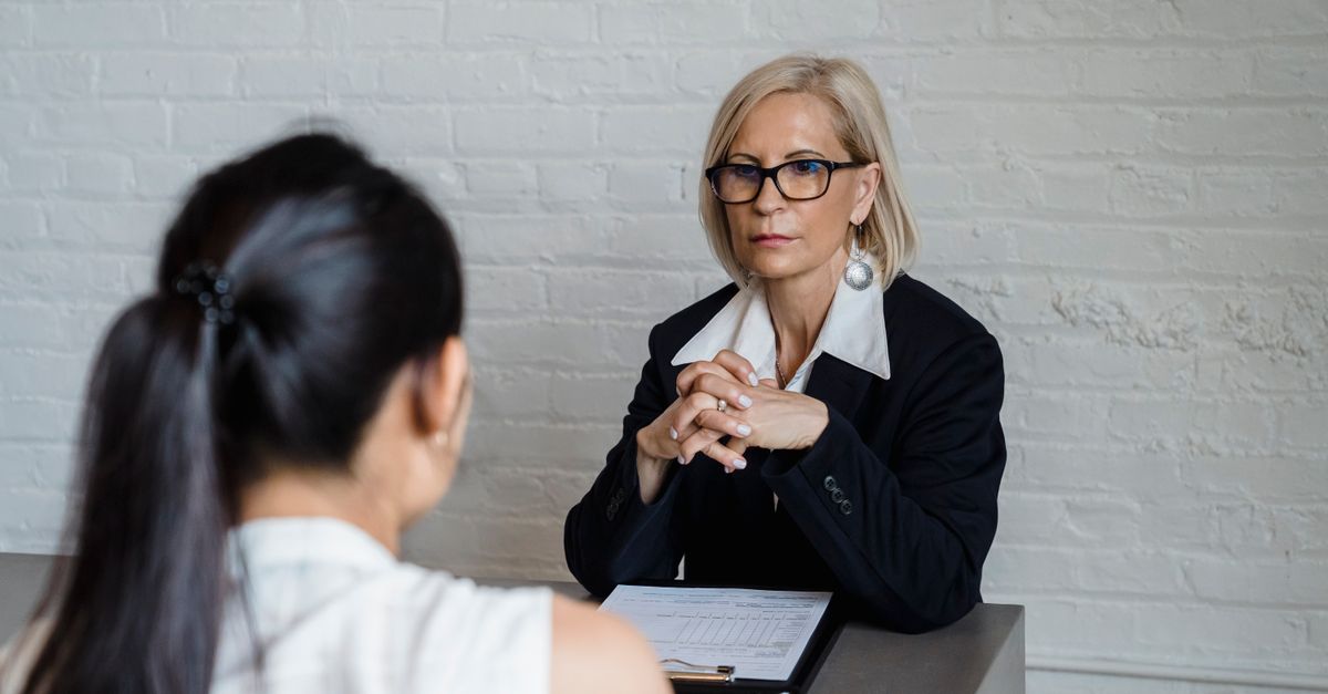 Professional businesswoman in a black blazer conducting an interview indoors.