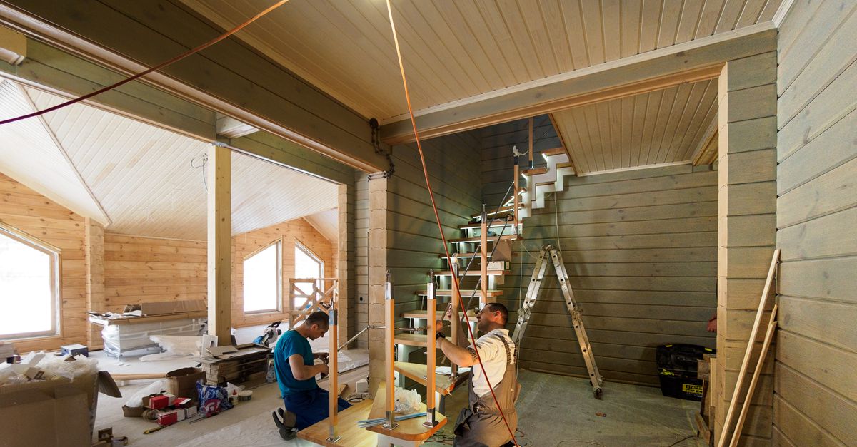 Carpenters skillfully assembling a modern wooden staircase inside a newly constructed home interior.