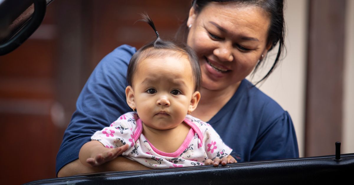 A mother joyfully holds her baby, showcasing a moment of family affection and happiness.