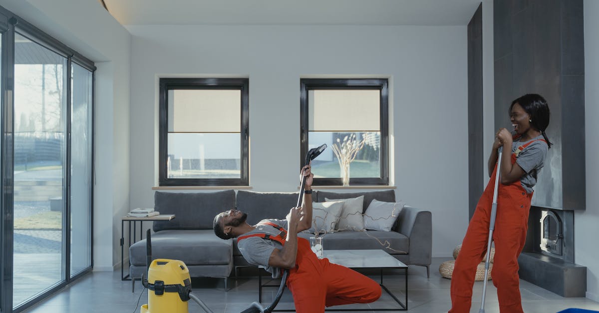 Fun and engaging cleaning session with a man and woman in overalls using cleaning tools in a modern living room.
