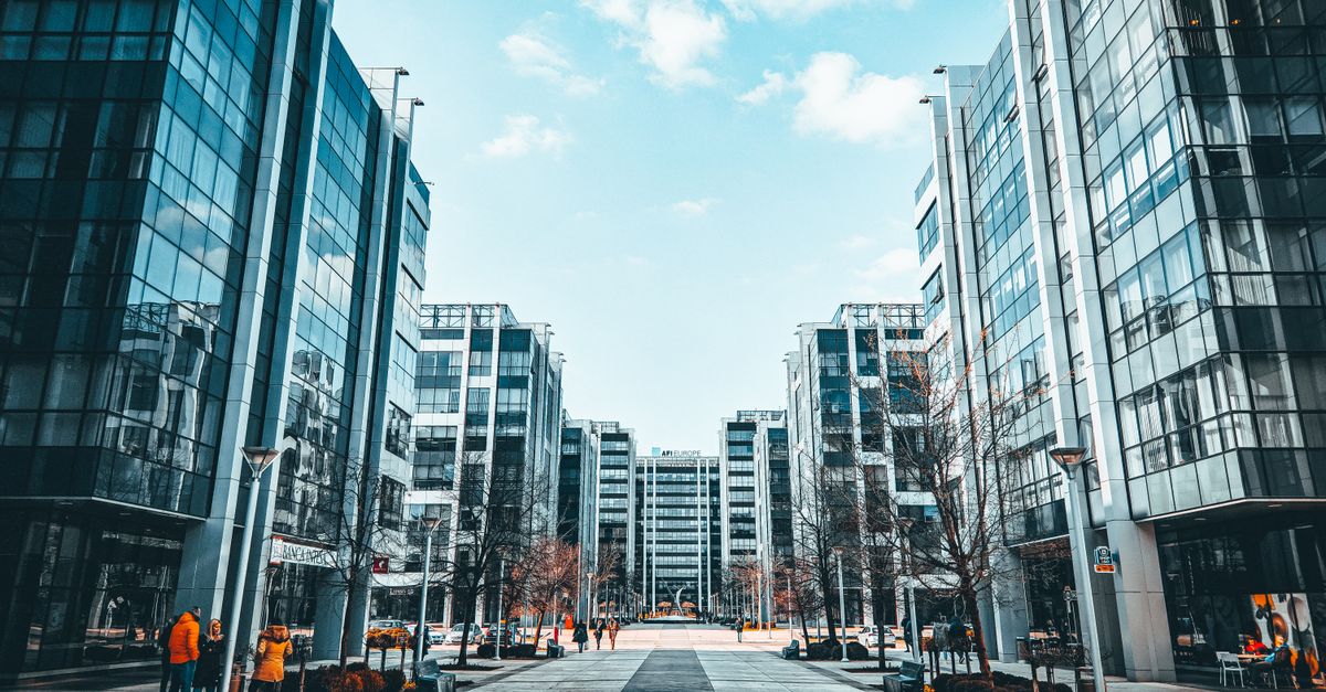 Contemporary urban environment featuring modern glass office buildings along a sidewalk.