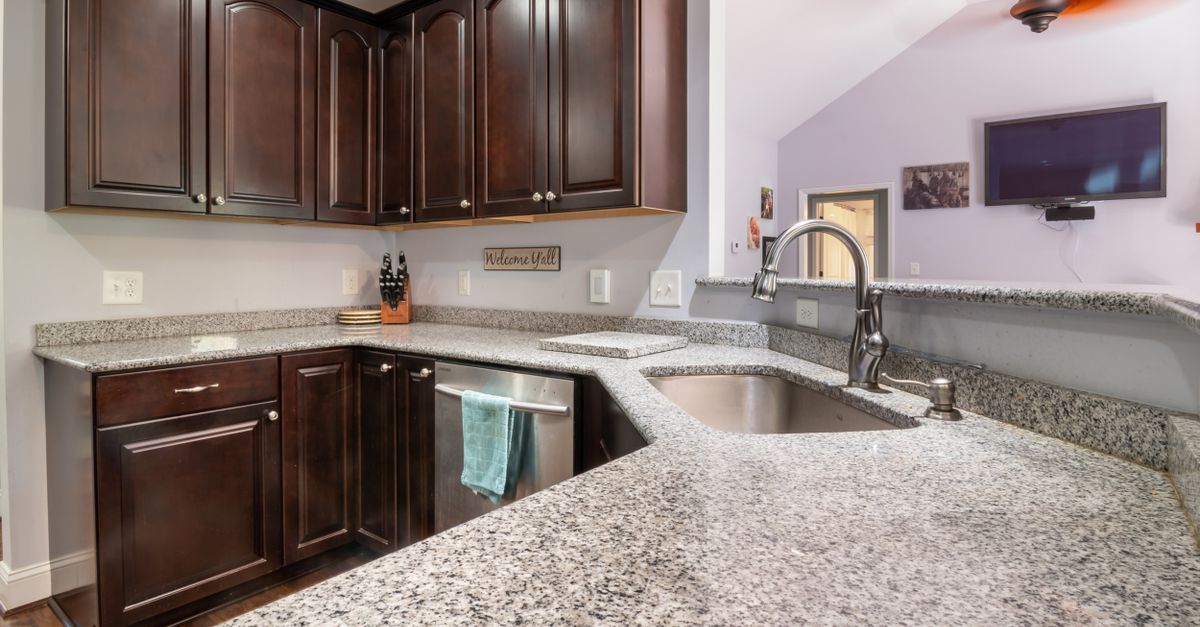 Contemporary kitchen design featuring granite countertops, dark wooden cabinets, and stainless steel appliances.