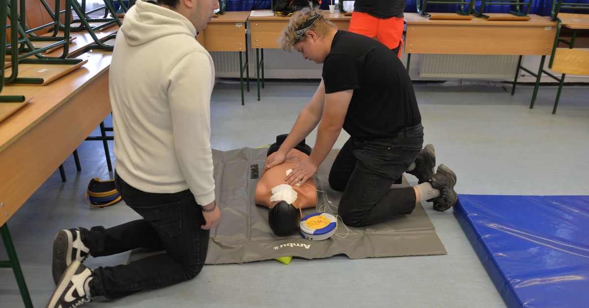 CPR training session with a dummy in a classroom environment.