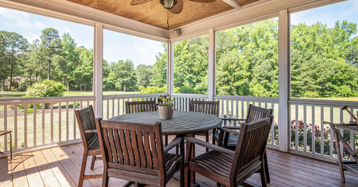Spacious outdoor patio featuring wooden furniture and scenic garden view, perfect for relaxation.