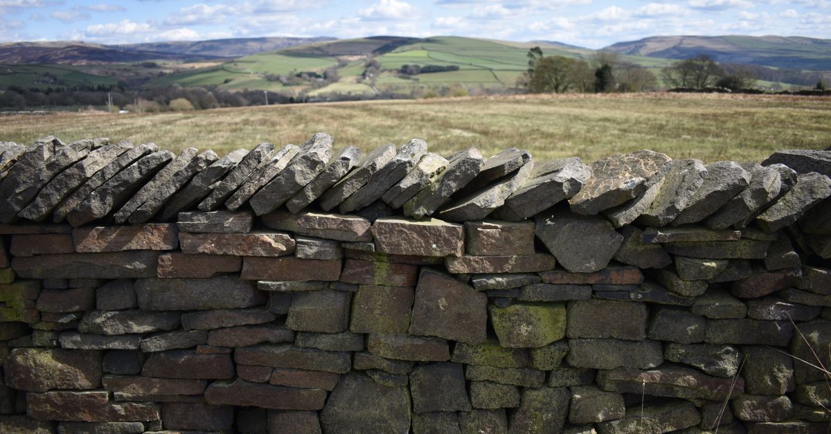 Beautiful English countryside landscape with traditional dry stone wall and rolling hills.