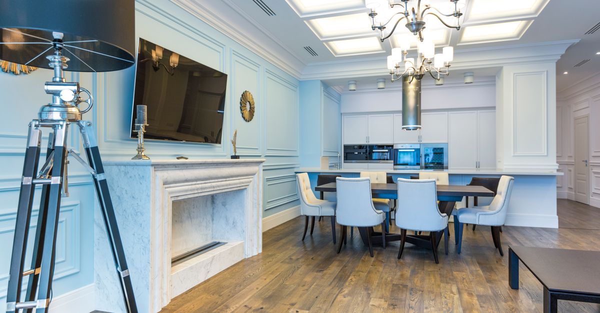 Spacious interior dining room featuring a chic chandelier, wooden floor, and marble fireplace.