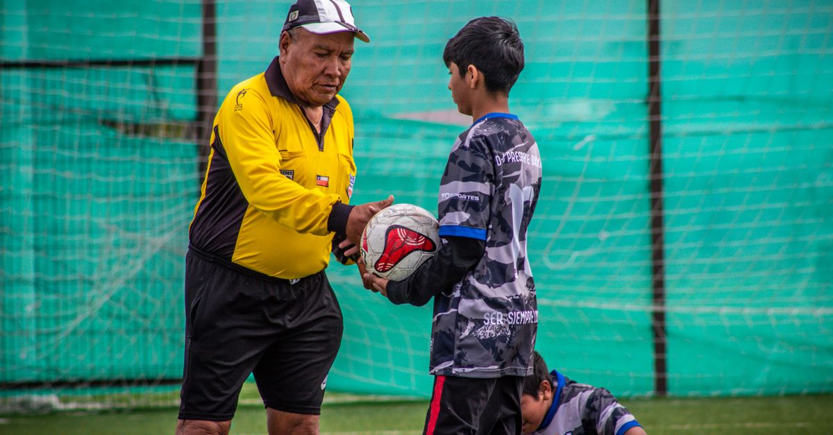An adult coach and young players during a soccer practice session outdoors in Chile.