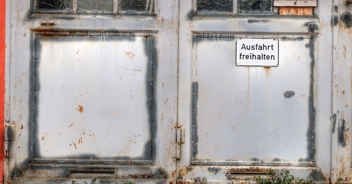 Weathered garage door with a German sign reading 'Keep Exit Clear.'