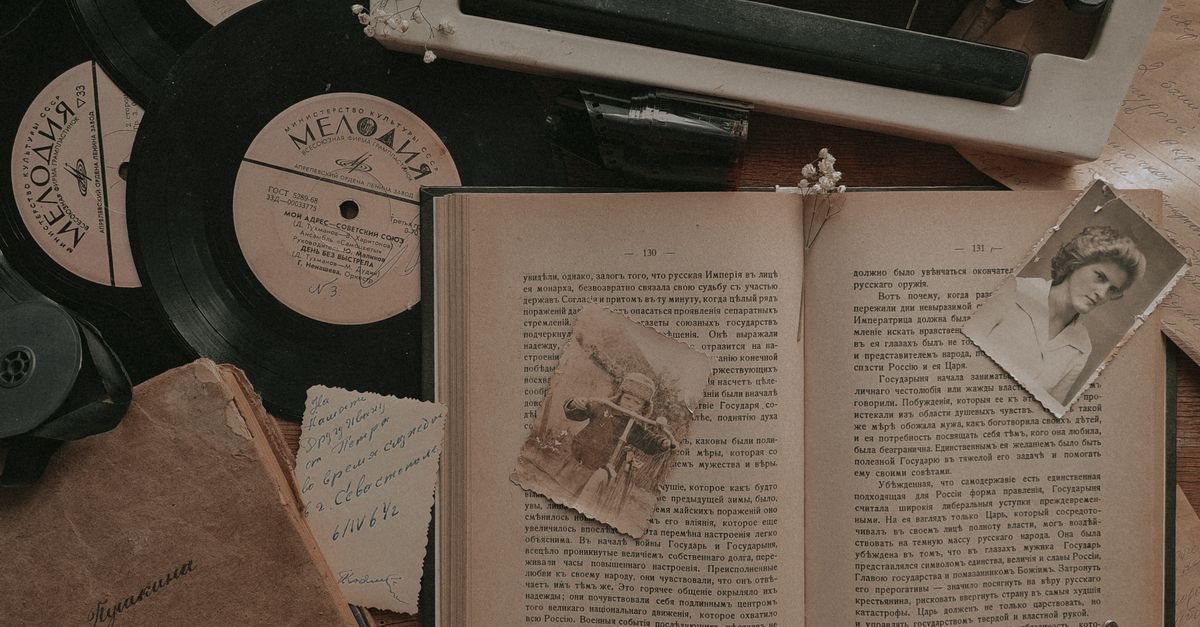 A nostalgic still life featuring a typewriter, vinyl records, and an open book.