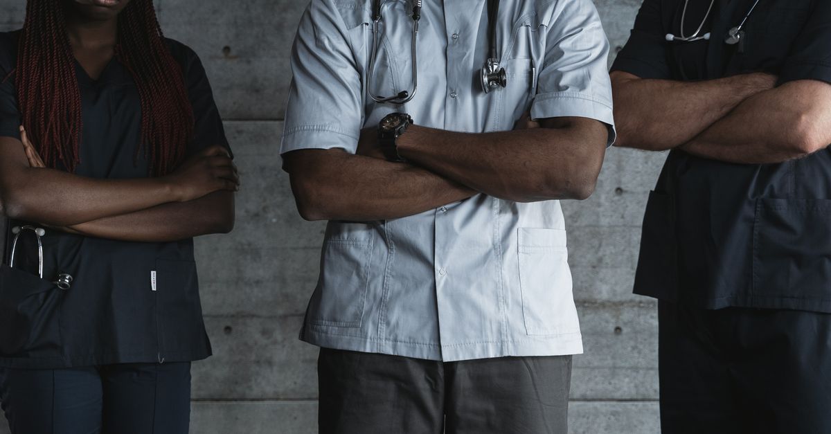 Group of medical professionals standing confidently with folded arms in uniform.