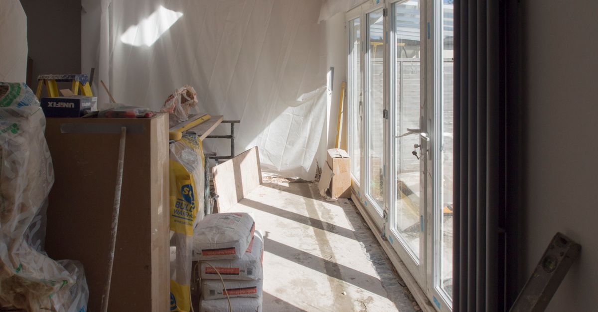 A construction area featuring renovation work in progress with large windows bringing in natural light.