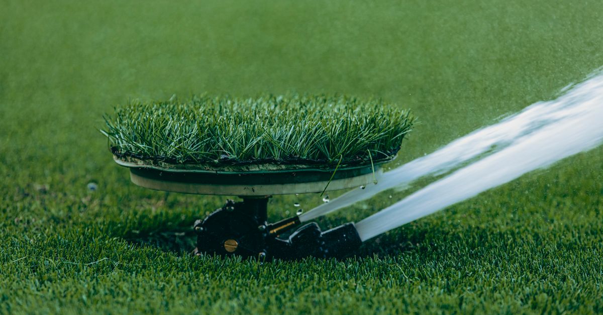 A close-up of an automated lawn sprinkler in action, showcasing efficient water usage on lush grass.