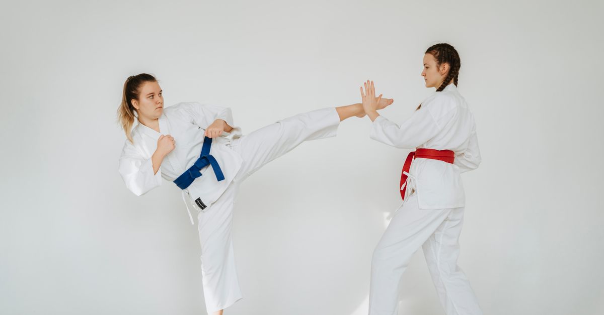 Dynamic shot of two women practicing martial arts techniques in a studio setting.