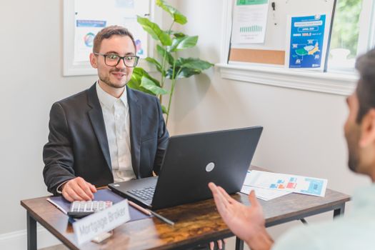 A mortgage broker and client discussing loan options in a modern office setting.