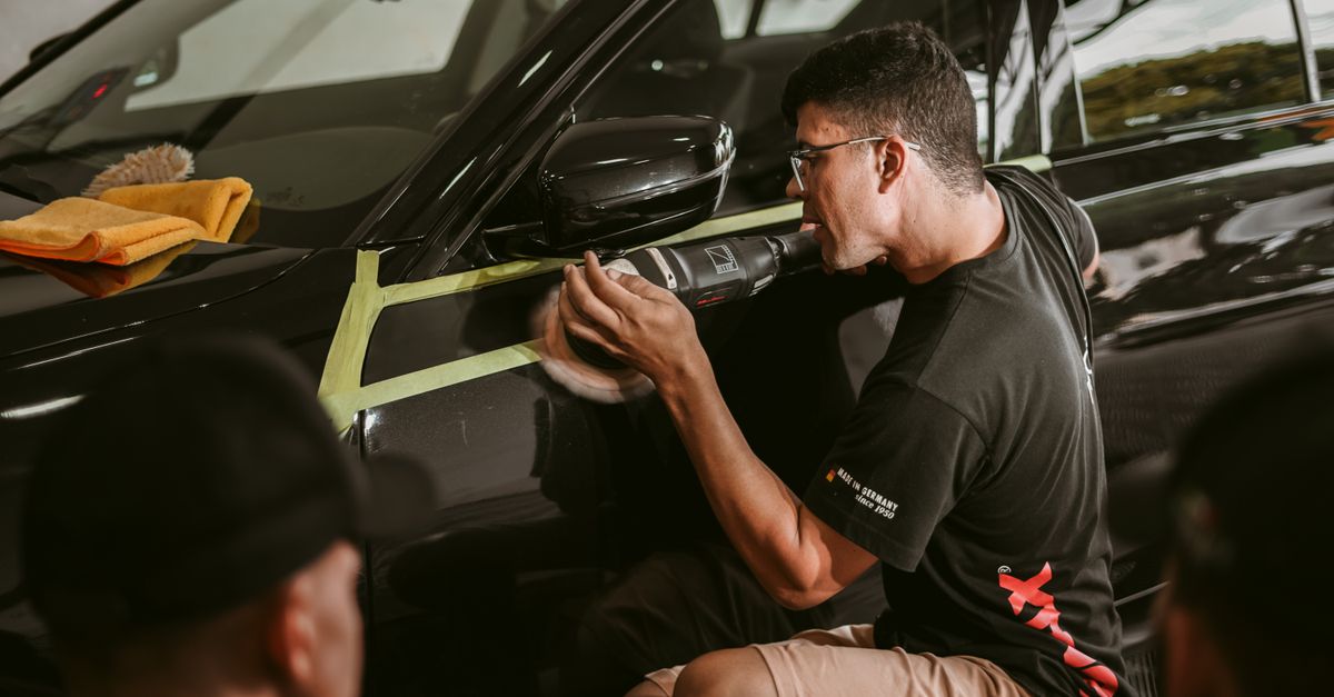 A man meticulously polishes a car, showcasing precision in an automotive workshop.