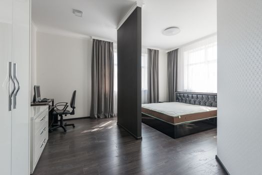 Spacious modern bedroom interior with a minimalist design and home office area.