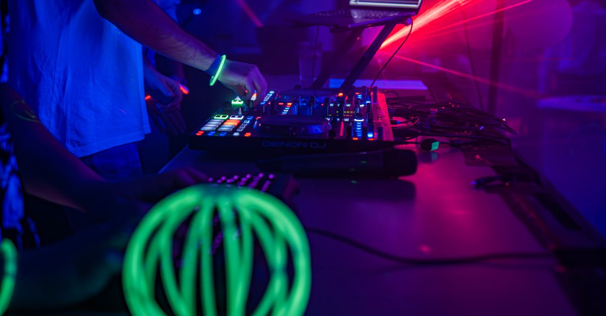 DJ mixing music at a nightclub with vibrant neon lights and professional sound equipment.