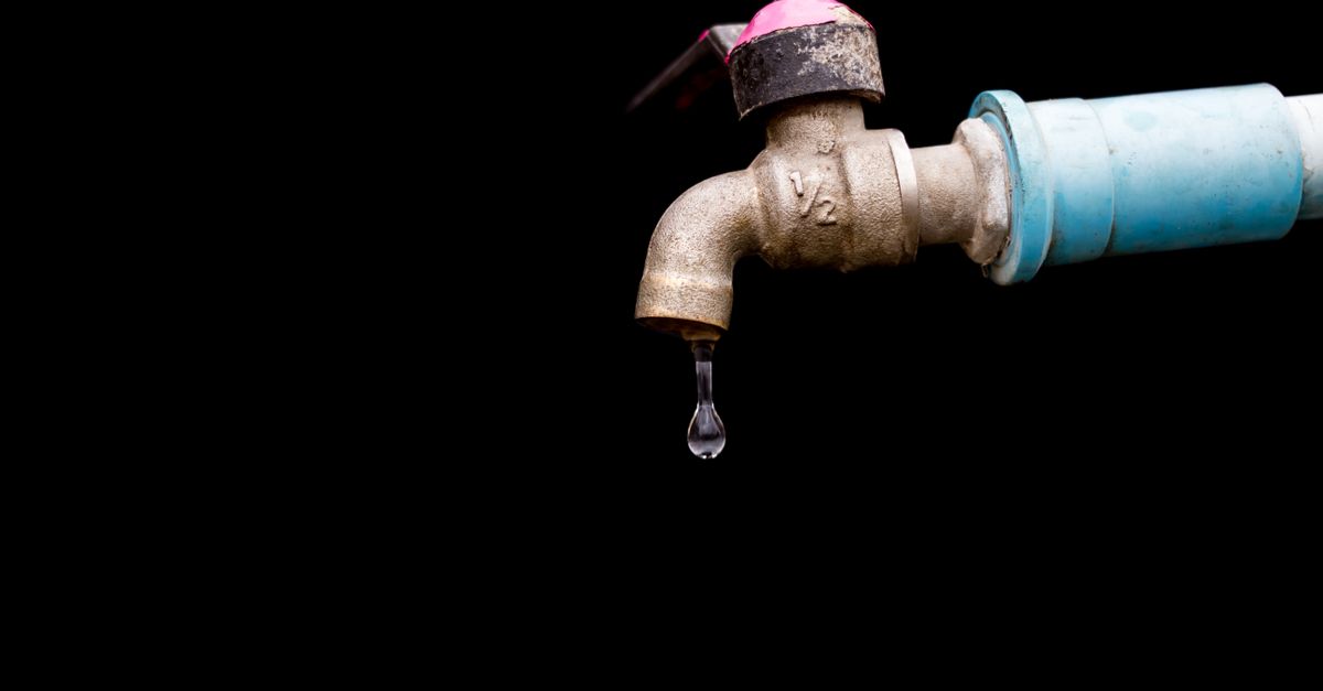 A detailed view of a metal faucet with a single water drop against a black background.