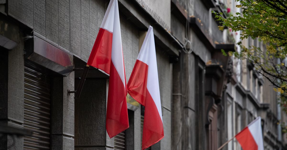 Polish flags hanging on a historic urban building, symbolizing national pride.