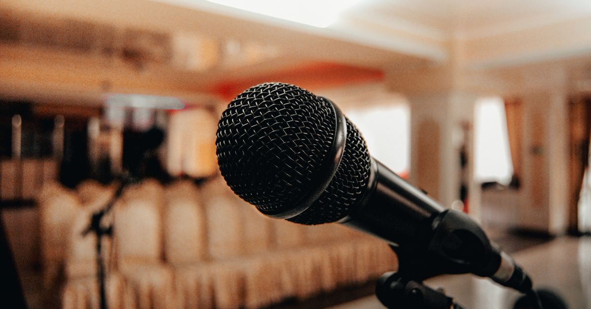 Closeup of black modern microphone on stand placed in spacious meeting room with chairs