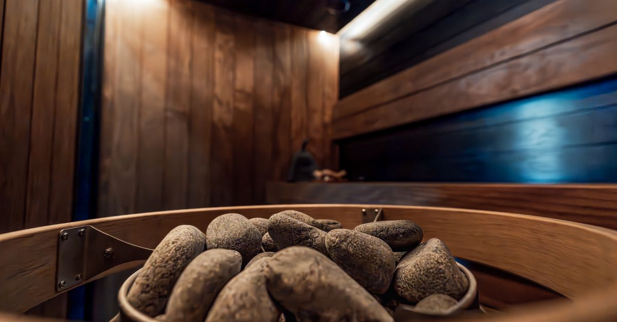 Elegant modern indoor sauna featuring dark wood and electric heater surrounded by stylish lighting.