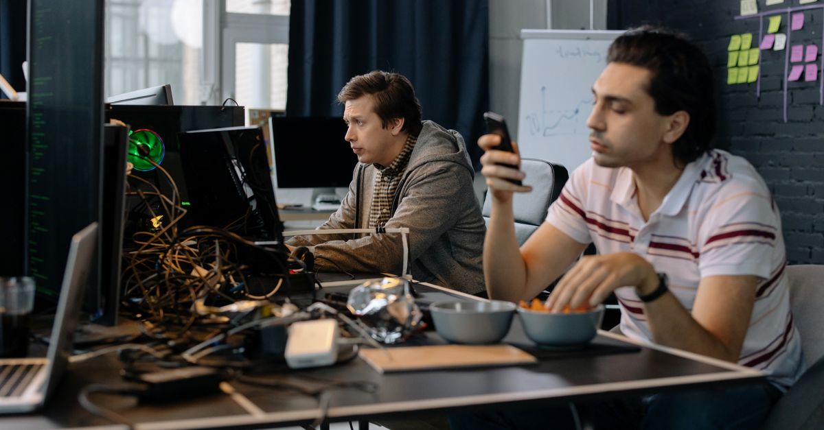Two men working in a modern office setup, focused on technology and collaboration.