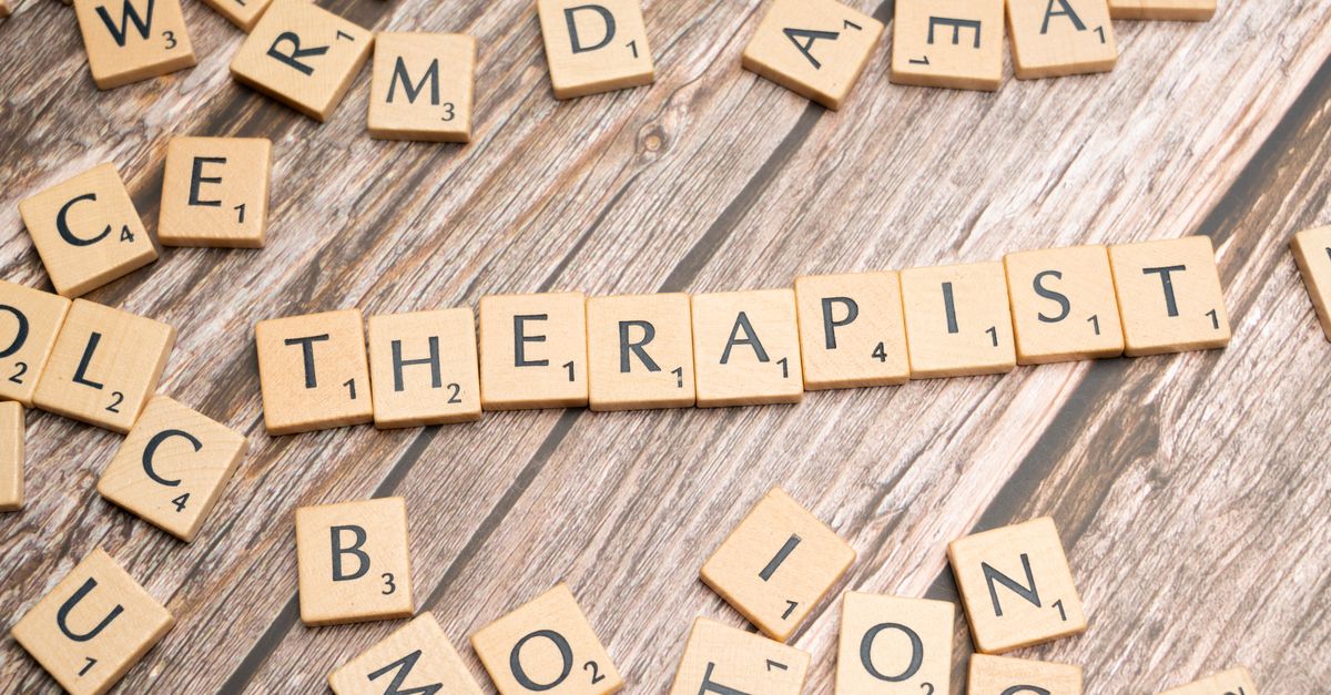 Wooden letter tiles on a rustic surface spell the word 'Therapist'.
