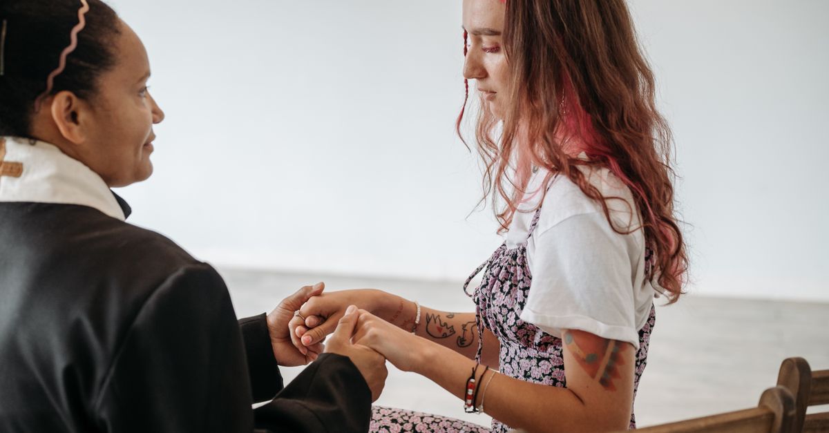 A pastor holds hands with a woman in a candid moment of connection and faith.