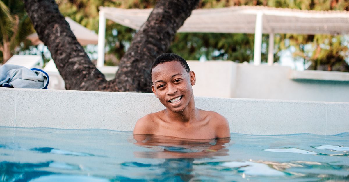 A happy man enjoying a relaxing swim in an outdoor pool during summer.