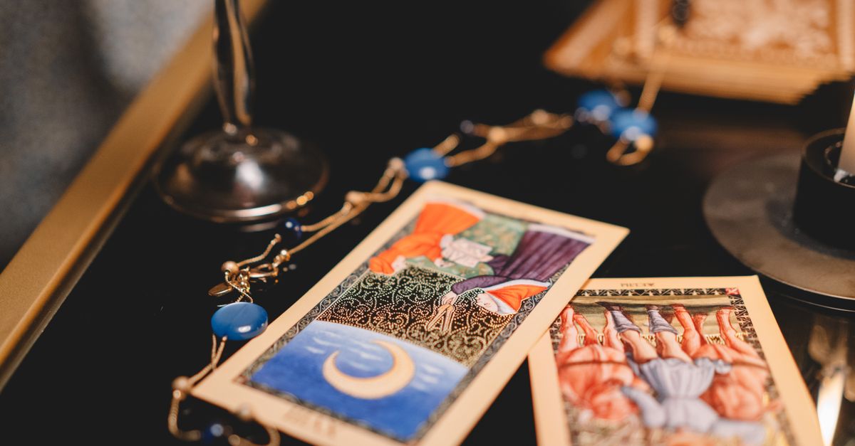 Close-up view of tarot cards on a table with a wineglass and mystical elements.
