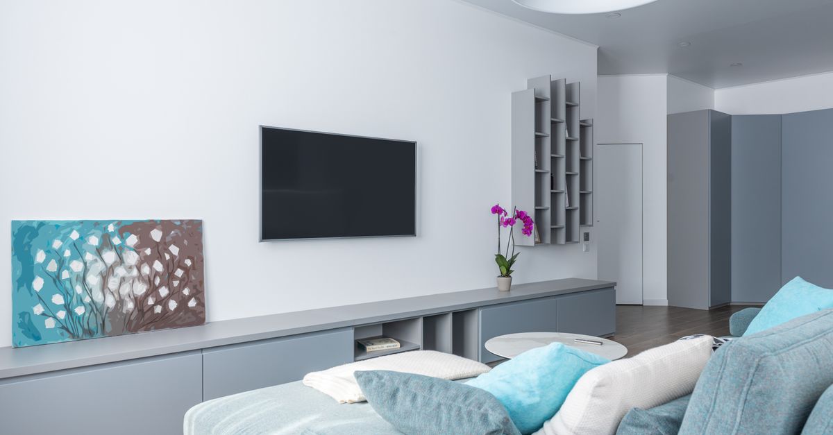 Modern interior of spacious living room decorated with gray shelves purple potted flower and picture