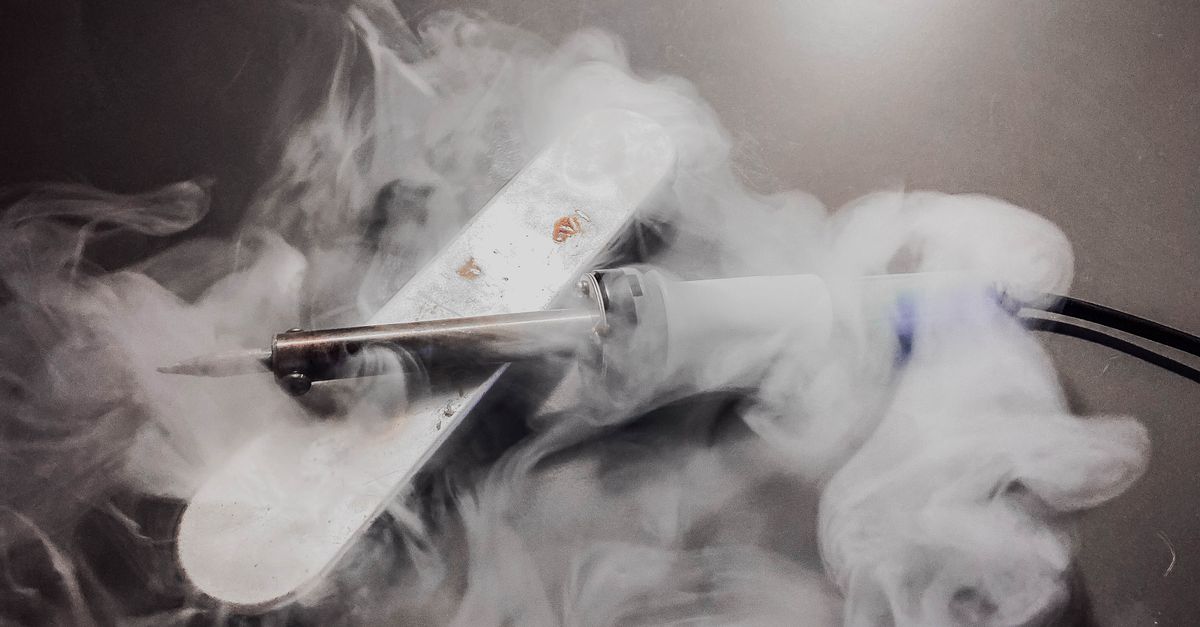Detailed image of a soldering iron emitting smoke, showcasing its heated tip and white fumes.