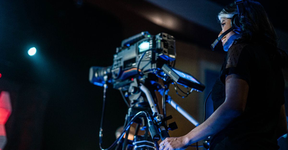 Low angle of happy woman in headset smiling and recording video of music show