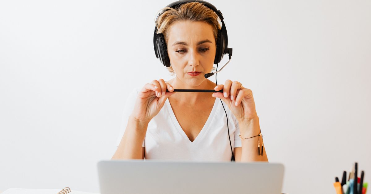Adult woman in headphones using laptop for remote work in a home office setting.