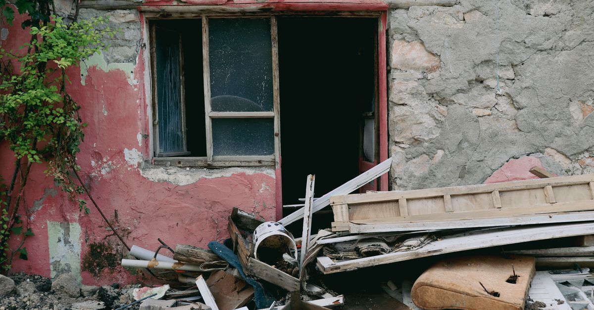 A damaged building facade showing broken windows and scattered rubble, illustrating urban decay.