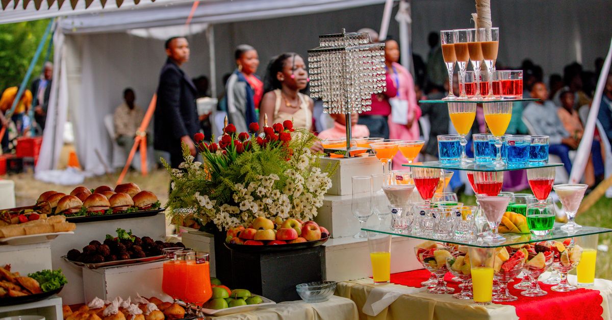 Elegant outdoor buffet setup with vibrant drinks and food at a wedding event.