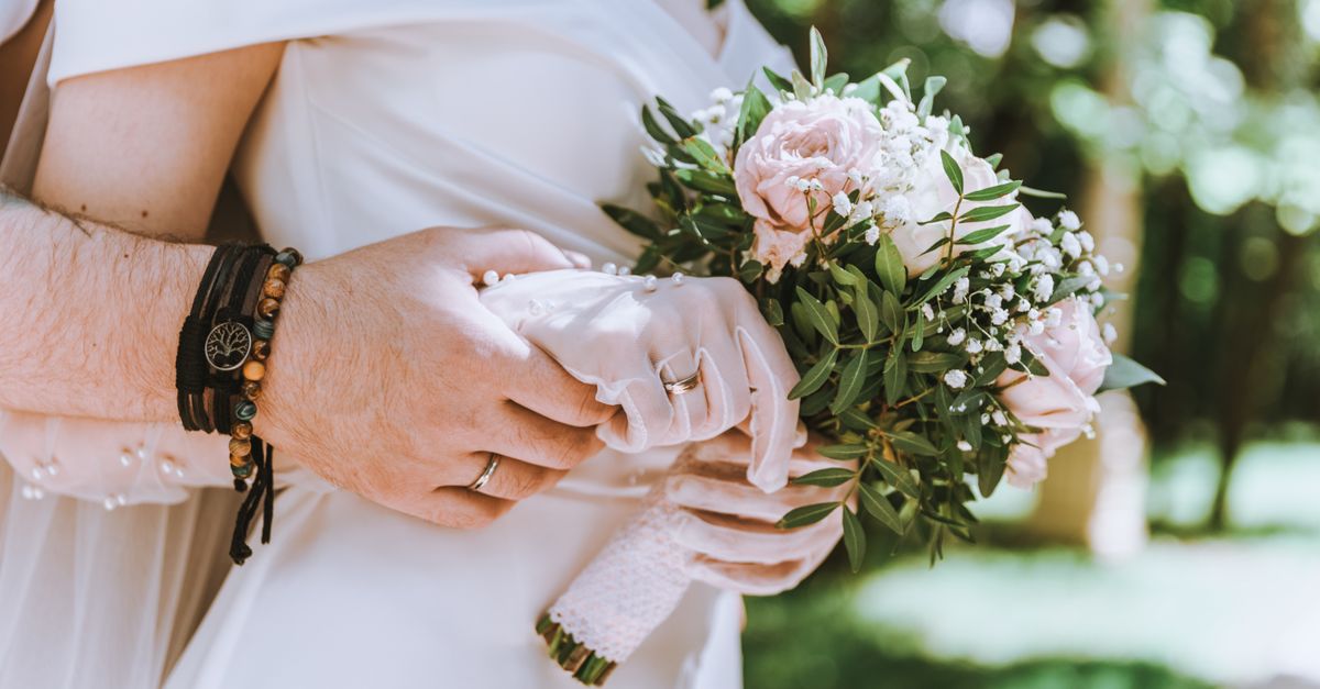 Close-up of a bride and groom holding a floral bouquet, symbolizing love and marriage.